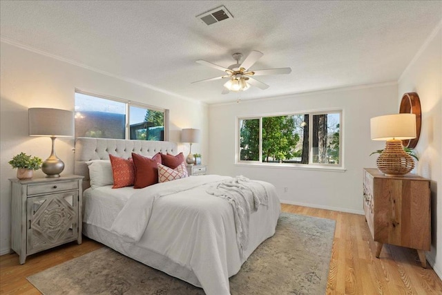 bedroom with multiple windows, crown molding, ceiling fan, and light hardwood / wood-style flooring