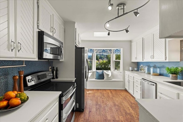 kitchen with stainless steel appliances, white cabinets, and light hardwood / wood-style flooring