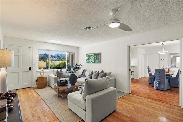 living room featuring ceiling fan, wood-type flooring, and a textured ceiling