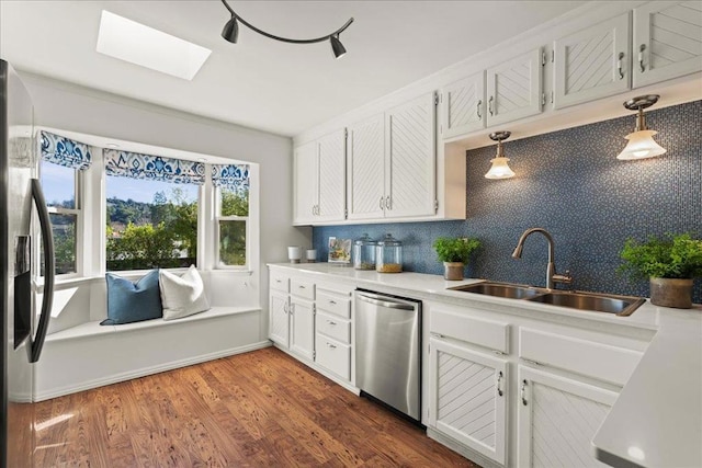 kitchen with sink, white cabinetry, a skylight, stainless steel appliances, and decorative backsplash