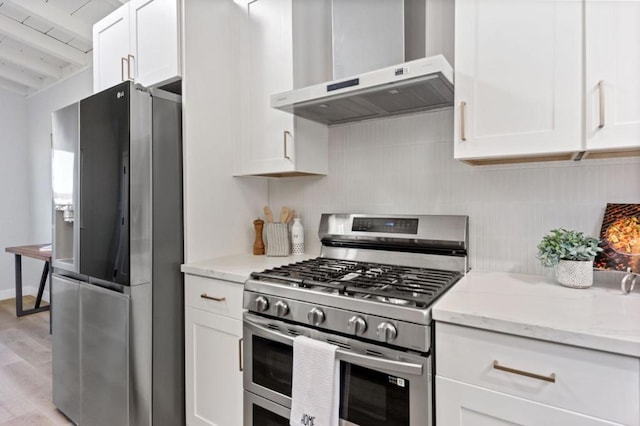 kitchen featuring white cabinets, stainless steel appliances, light stone countertops, and wall chimney range hood