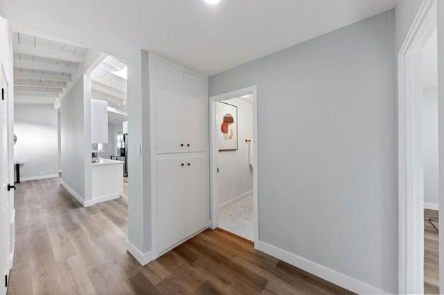 hall featuring vaulted ceiling with beams and light wood-type flooring