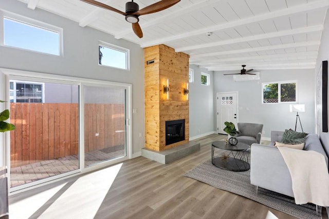 living room with lofted ceiling with beams, a tiled fireplace, hardwood / wood-style flooring, ceiling fan, and wood ceiling