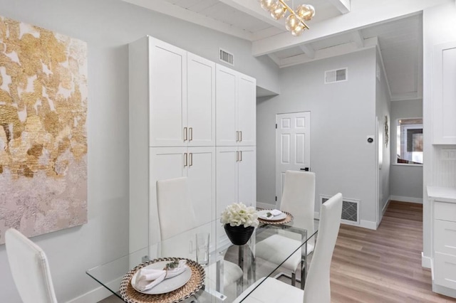 dining space featuring vaulted ceiling with beams, a chandelier, and light hardwood / wood-style floors