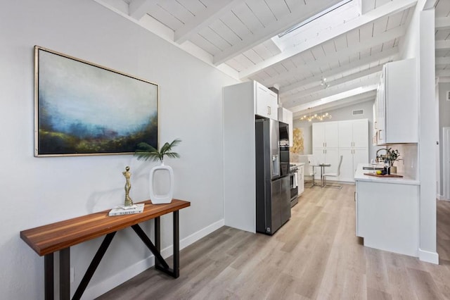 kitchen featuring vaulted ceiling with beams, a chandelier, light wood-type flooring, stainless steel appliances, and white cabinets