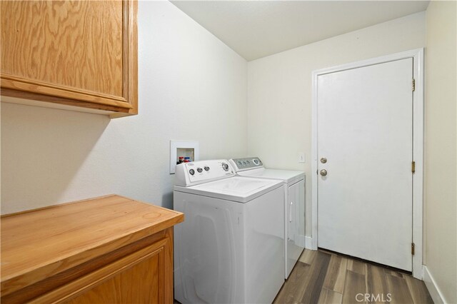 clothes washing area featuring washer and dryer, cabinets, and dark hardwood / wood-style flooring