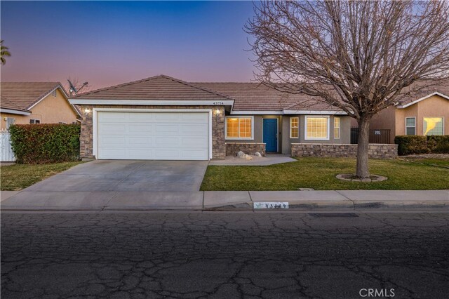 single story home featuring a garage and a lawn