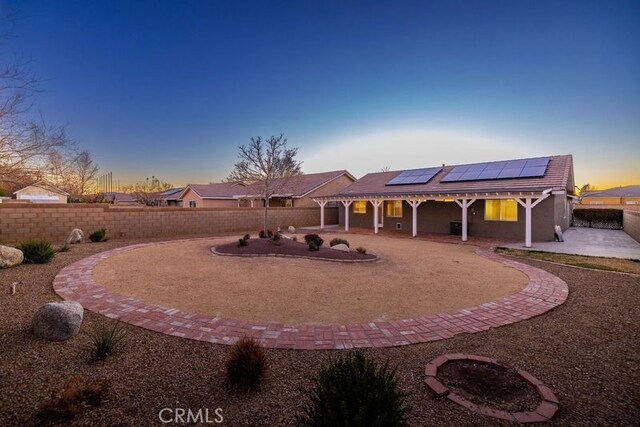 back house at dusk with solar panels and a patio