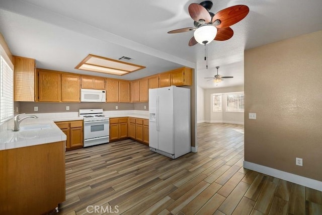 kitchen featuring dark wood-type flooring, ceiling fan, sink, and white appliances