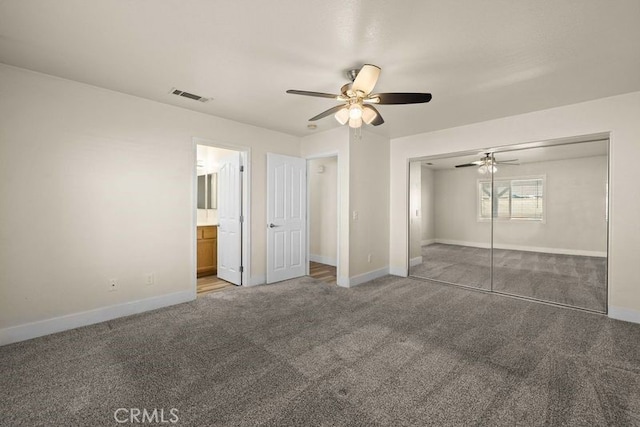 unfurnished bedroom with ceiling fan, ensuite bathroom, a closet, and dark carpet