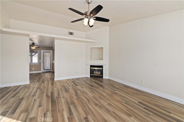 unfurnished living room featuring ceiling fan and hardwood / wood-style floors