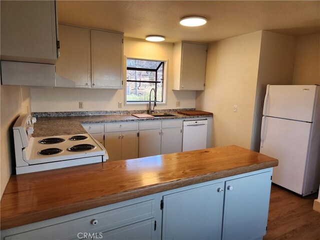 kitchen with sink, white appliances, white cabinets, and wooden counters
