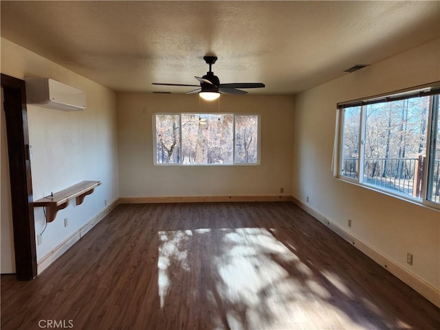 unfurnished room with ceiling fan, a textured ceiling, dark hardwood / wood-style flooring, and a wall mounted air conditioner