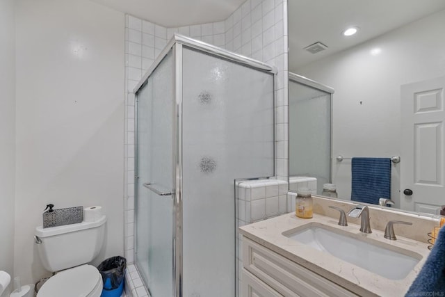 bathroom featuring toilet, a shower with shower door, and vanity