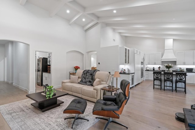 living room with high vaulted ceiling, beamed ceiling, and light hardwood / wood-style flooring