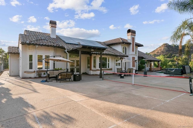 rear view of house featuring solar panels, an outdoor living space, a mountain view, and a patio