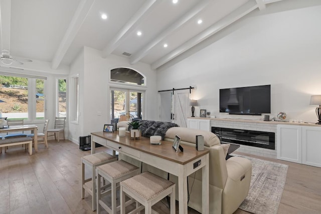 living room featuring ceiling fan, plenty of natural light, beamed ceiling, and a barn door