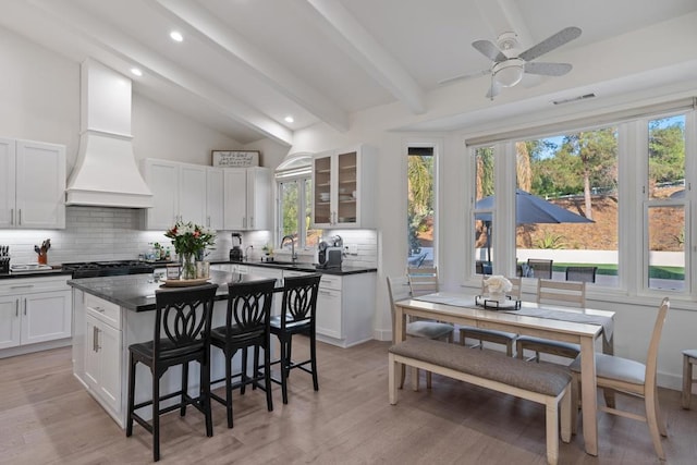 kitchen with sink, white cabinets, lofted ceiling with beams, and custom exhaust hood