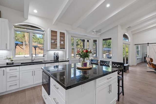 kitchen with tasteful backsplash, a barn door, sink, built in microwave, and white cabinets