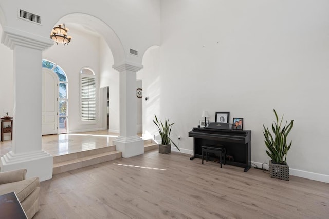 interior space featuring decorative columns, a high ceiling, and light hardwood / wood-style flooring