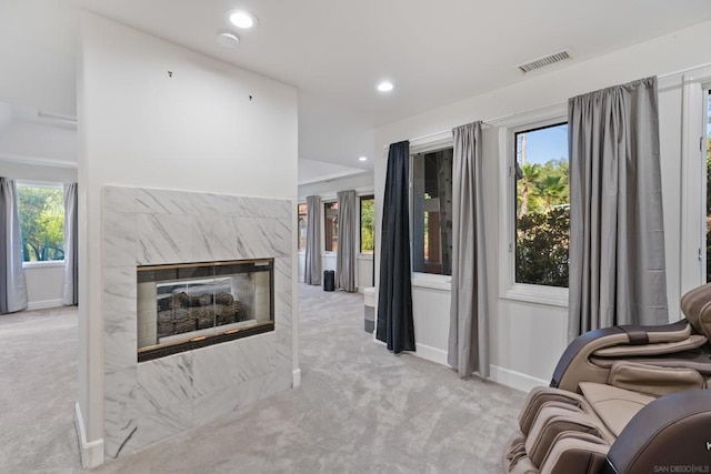 living room featuring light carpet and a high end fireplace