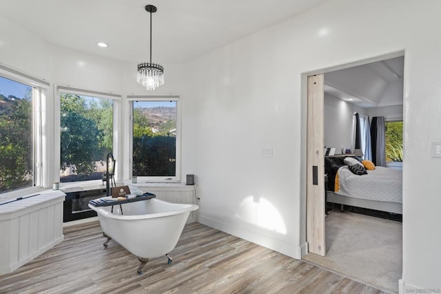 bathroom with a bathtub, wood-type flooring, and a notable chandelier