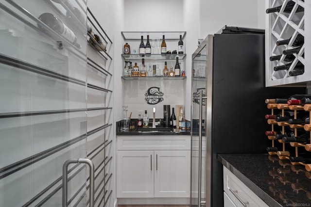 bar featuring white cabinets and dark stone countertops