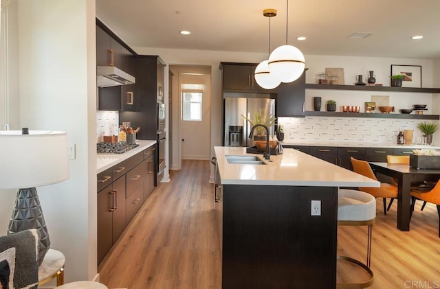 kitchen with pendant lighting, sink, light hardwood / wood-style flooring, an island with sink, and stainless steel appliances