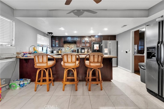 kitchen featuring tasteful backsplash, a kitchen breakfast bar, stainless steel fridge, wall oven, and stainless steel fridge with ice dispenser