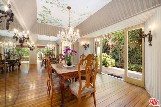 dining space with hardwood / wood-style flooring, a wealth of natural light, and a notable chandelier