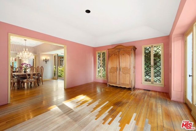 interior space with french doors, a chandelier, vaulted ceiling, and light wood-type flooring