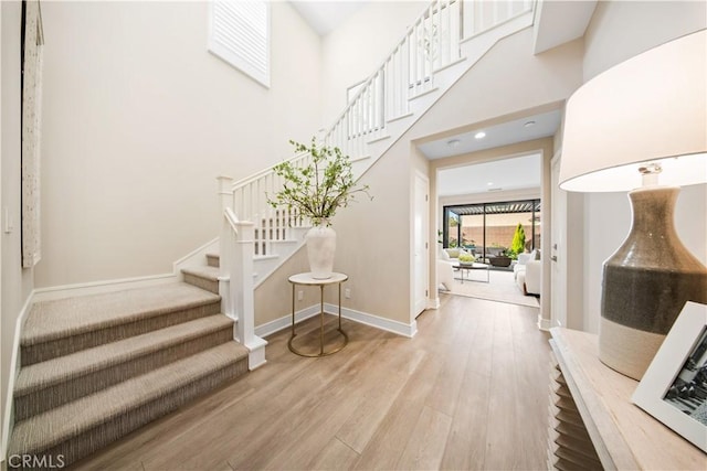 foyer with wood-type flooring and a towering ceiling