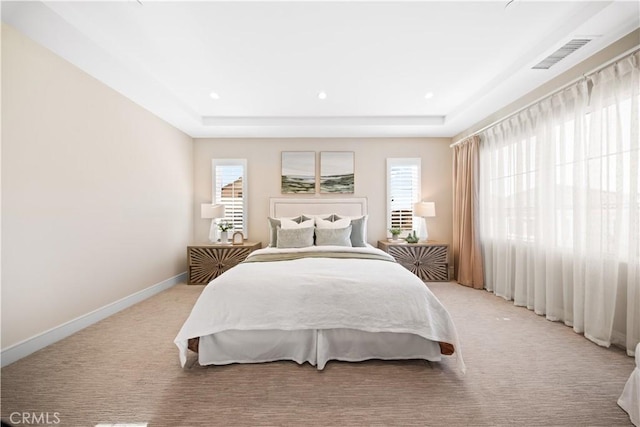 carpeted bedroom with multiple windows and a tray ceiling