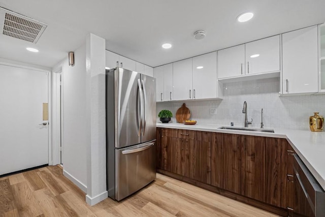 kitchen with sink, stainless steel fridge, light wood-type flooring, and dark brown cabinetry