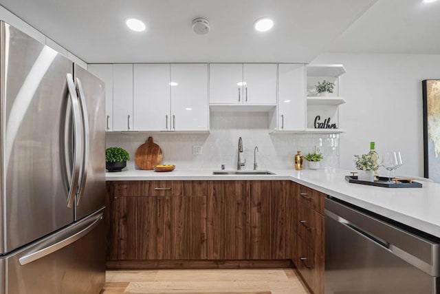 kitchen featuring appliances with stainless steel finishes, dark brown cabinetry, white cabinets, backsplash, and sink