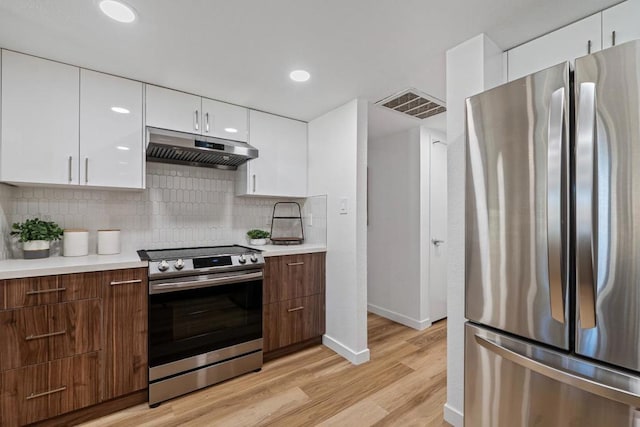 kitchen featuring appliances with stainless steel finishes, light hardwood / wood-style floors, decorative backsplash, and white cabinetry