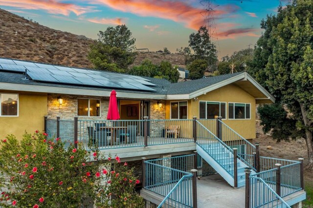 back house at dusk featuring solar panels and covered porch