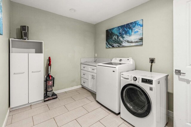 clothes washing area featuring cabinets and washer and dryer