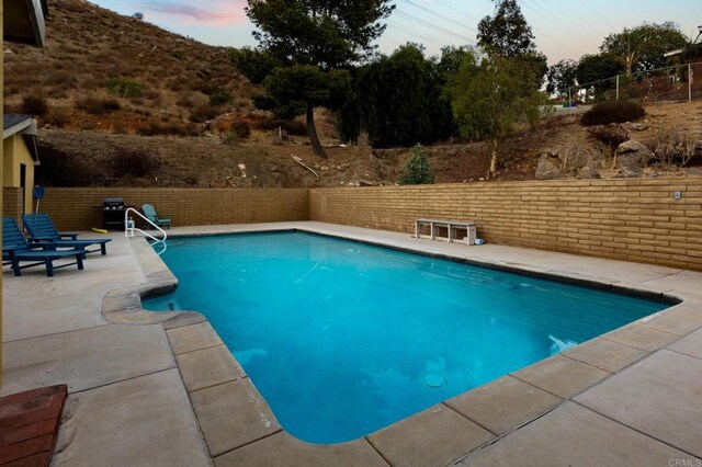 pool at dusk featuring a patio