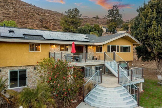 back house at dusk featuring a porch and solar panels