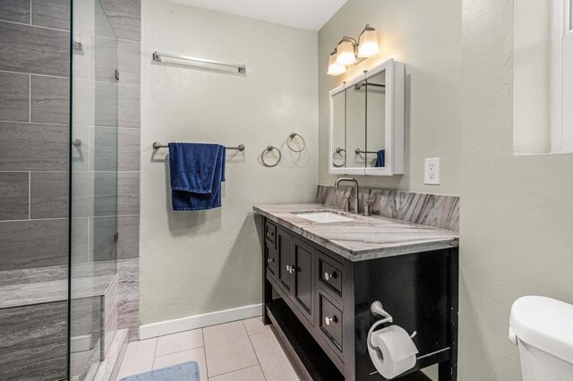 bathroom with vanity, toilet, tile patterned flooring, and a tile shower