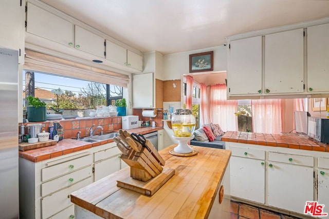 kitchen with white cabinetry, appliances with stainless steel finishes, tile counters, light tile patterned flooring, and sink