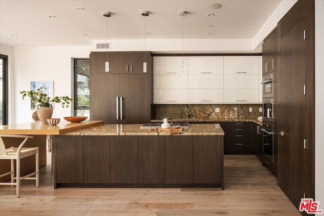 kitchen with stainless steel appliances, tasteful backsplash, light wood-type flooring, hanging light fixtures, and white cabinets