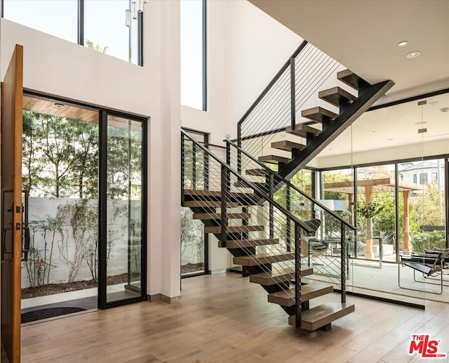 staircase featuring a towering ceiling and hardwood / wood-style flooring