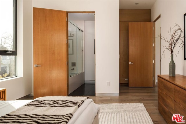 bedroom with dark wood-type flooring, a closet, and connected bathroom