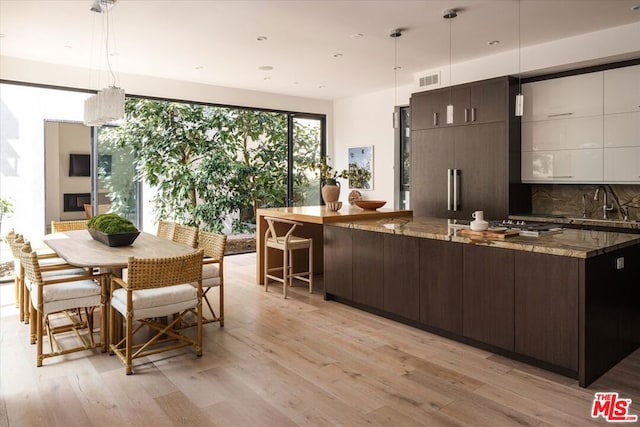 kitchen with dark brown cabinets, dark stone counters, and pendant lighting