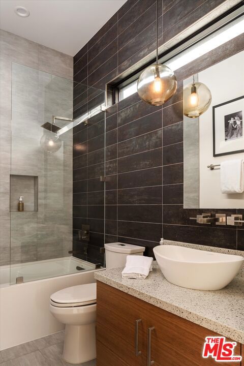 full bathroom featuring tile walls, toilet, vanity, and tiled shower / bath