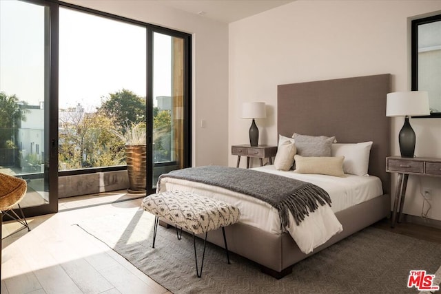 bedroom with access to outside, wood-type flooring, and multiple windows