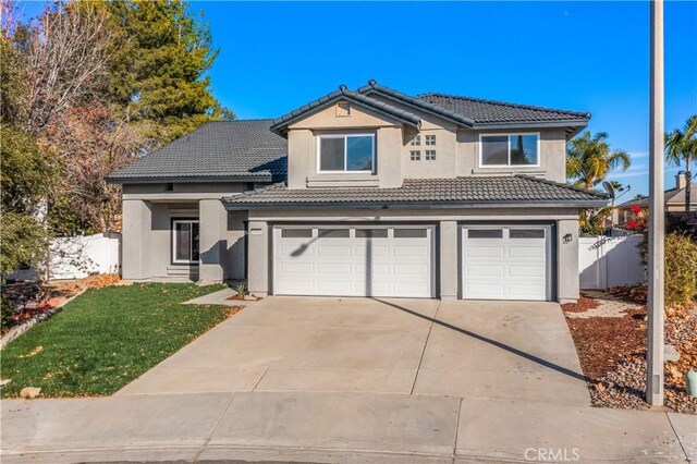 traditional-style house with a tiled roof, an attached garage, and stucco siding