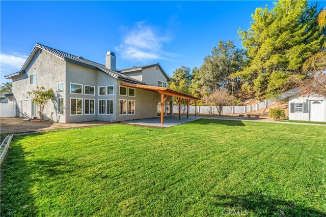 back of house featuring a storage unit, a patio area, and a yard